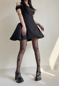 Close-up detail shot of black fishnet tights featuring cute 3d bows for women style.