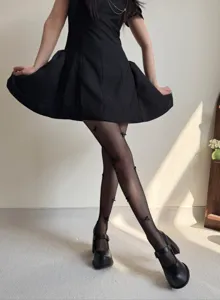 Close-up detail of black fishnet tights featuring cute handmade 3D bows, balletcore style.