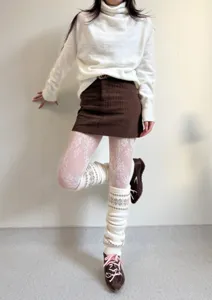 Vue détaillée de collants résille en dentelle florale blanche et de jambières tricotées.
