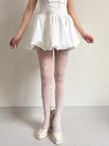 Close-up detail showing handmade 3D bows on white fishnet tights, balletcore style, delicate mesh.