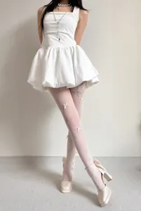 Detailed shot of white fishnet tights featuring cute 3D handmade bows, balletcore aesthetic.