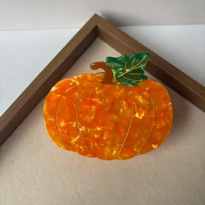 Close-up detail shot of cute pumpkin hair claw clip, creative cartoon hair accessory.