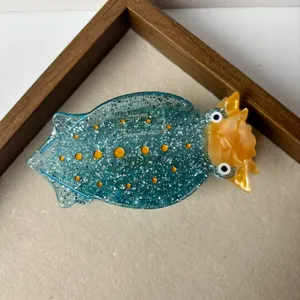 Cute creative sea slug hair claw clip detail, sparkling blue resin hair accessory with yellow details.