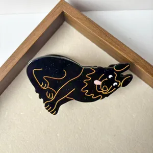 Detailed close-up of a cute black dog hair claw clip with gold outline design for women.