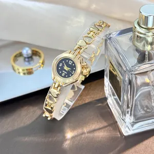 Close-up detail of luxury gold quartz watch featuring hollow heart bracelet and black dial.