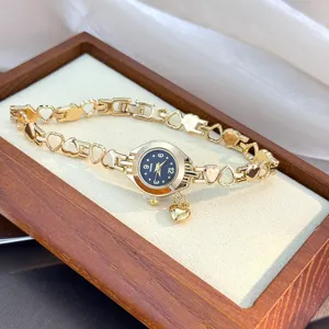 Close-up of the elegant gold-colored quartz watch with heart-linked bracelet and charm.