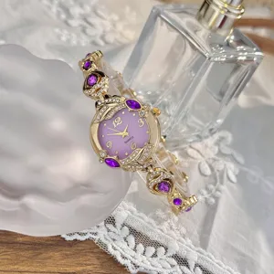 Vista detallada de reloj de cuarzo para mujer con esfera morada y pulsera dorada con cristales.