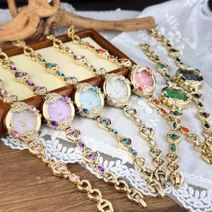 Vista detallada de reloj de pulsera de cuarzo para mujer con cadena dorada y gemas.