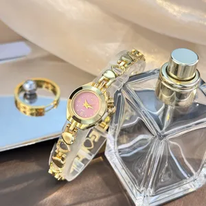 Close-up detail of the delicate gold quartz watch featuring hollow heart links and a pink dial.