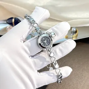 Detail view of dainty hollow heart bracelet quartz watch with charming pendant design.