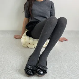 Détail en gros plan des collants à motif de losanges ajourés gris automne hiver pour femmes.