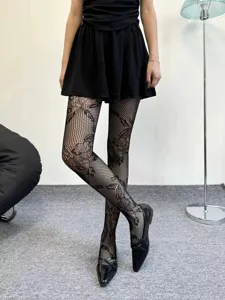 Close-up detail shot of black patterned fishnet tights featuring elegant floral lace design.