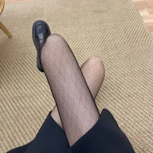 Black fishnet tights with seamless diamond pattern, high elasticity anti-snag hosiery detail.