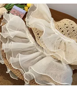 Close-up detail view of summer women's straw sun hat with white chiffon ruffles and pearls.