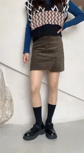 Stylish women outfit featuring knit vest, corduroy skirt, pantyhose and platform shoes.