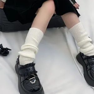 White knitted leg warmers stack socks paired with black platform shoes for a stylish look.