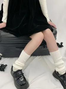 Detailed shot of white knitted leg warmers styled with black platform shoes for winter outfits.