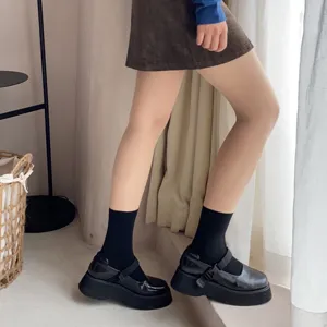 Detailed shot of stylish sheer pantyhose paired with black platform shoes for trendy look.