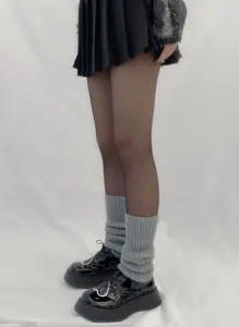 Detailed view of grey knit leg warmers slouch socks styled with platform shoes and pleated skirt.