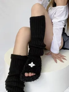 Detailed view of black knitted leg warmers paired with fluffy slippers featuring cross decor.
