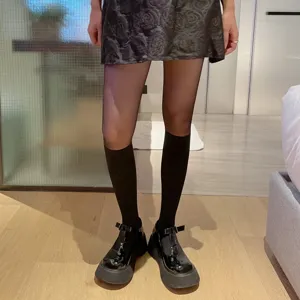 Black sheer tights with fake knee high socks detail and shiny platform shoes close up shot