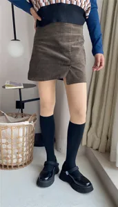 Detailed shot of trendy fake thigh-high socks fleece-lined pantyhose with corduroy skirt outfit.