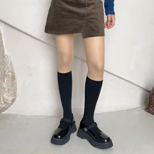 Detail shot of black platform Mary Jane shoes paired with socks and skirt, chic sweet cool style.