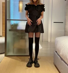 Detailed shot of stylish black dress and hosiery outfit in indoor setting, elegant look.