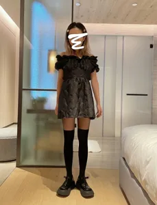Detailed shot of sexy black pantyhose and off-shoulder dress outfit, stylish look.
