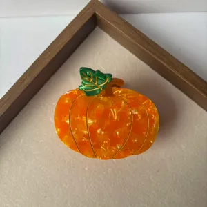 Orange pumpkin hair claw clip, cute autumn fruit hair accessory detail close-up view.