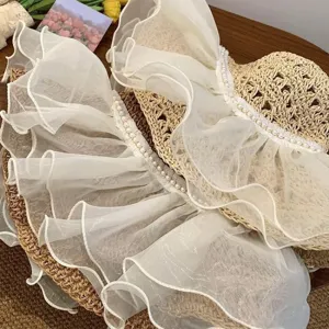Women's summer straw sun hat with wide brim, white lace ruffles and pearls for beach.