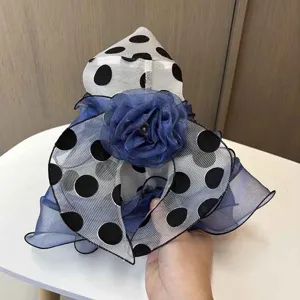 Nahaufnahme Detail von Organza schwarz weissen Pünktchen Sonnenhut mit blauer Blume.
