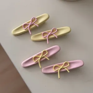Primo piano dettagliato di simpatici fermagli per capelli con fiocco in rosa e giallo pastello.