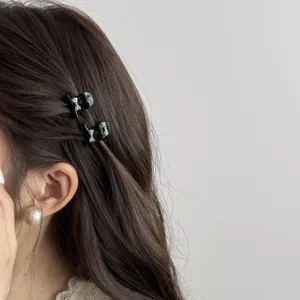 Mini black hair claw clips with crystal bow detail, perfect for side bangs and styling.