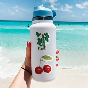 Detailed view of white insulated water bottle decorated with vintage stickers outdoors.
