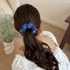 Dettaglio dell'elastico per capelli floreale blu legato in coda di cavallo, elegante.