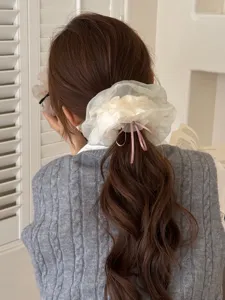 Dettaglio dell'elastico per capelli in rete bianca con grazioso fiocco rosa e fiore.