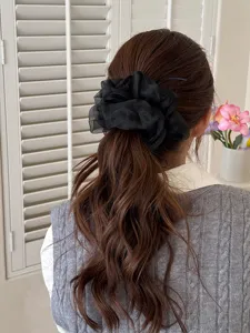 Vista dettagliata di un elegante scrunchie in rete nera indossato sulla coda, tessuto morbido.