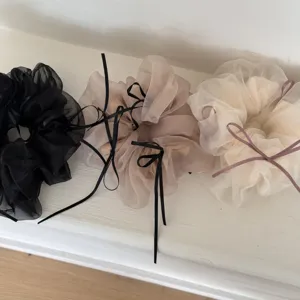 Dettaglio scrunchies in tulle con fiocco, elastici morbidi per eleganti acconciature a chignon.