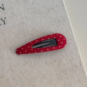 Detail van rode stoffen snap-haarspeld met stippen, schattig Koreaans haaraccessoire voor pony's.