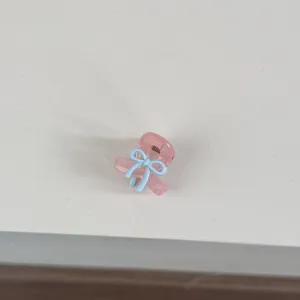 Detail view of a cute mini pink hair claw clip featuring a lovely light blue bow design.