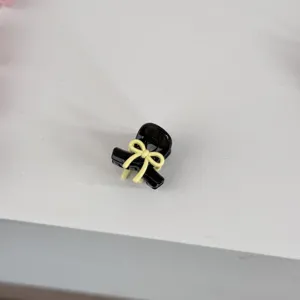 Mini black hair claw clip with a cute yellow bow design, detail view showing fine craft.