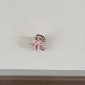 Mini hair claw clip detail view, cute pink bow design for sweet daily hairstyles and bangs.