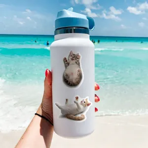 Cute cat stickers detail shot on white insulated water bottle outdoors near beach.