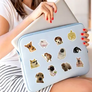 Close-up detail shot of light blue laptop sleeve decorated with funny dog meme stickers.