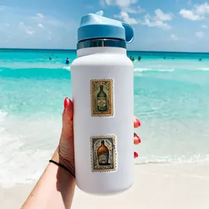 White stainless steel insulated water bottle with vintage stamp stickers for beach use.