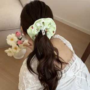 Primo piano dettagliato dell'elastico a quadri verdi con fragole e fiocco in pizzo bianco.