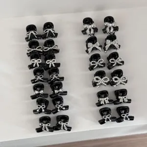 Detailed close-up view of cute black mini hair claw clips featuring sparkling silver bow designs.