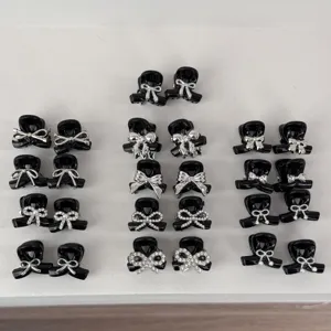 Closeup detail view of cute black mini hair claw clips set with sparkling silver bow designs.