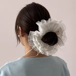 Nahaufnahme des eleganten weißen Spitzen-Haargummis mit zarter Schleife und Rüschen.